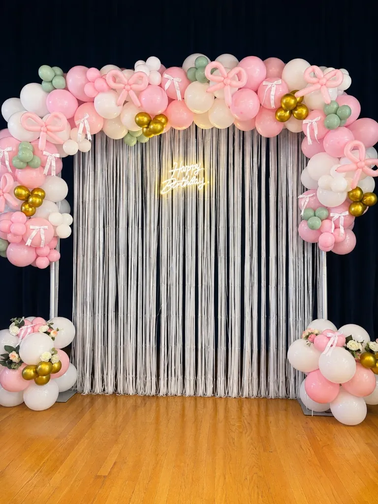 Pink and white balloon arch with bows and fringe backdrop