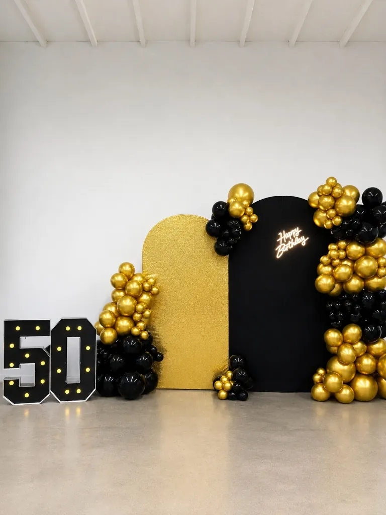 50th birthday party with black and gold balloons and marquee lights