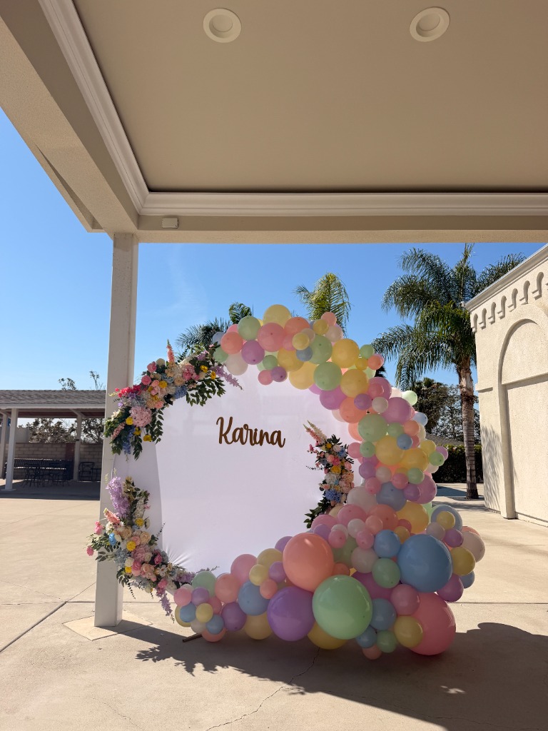 Pastel balloon arch and custom name backdrop for outdoor birthday celebration