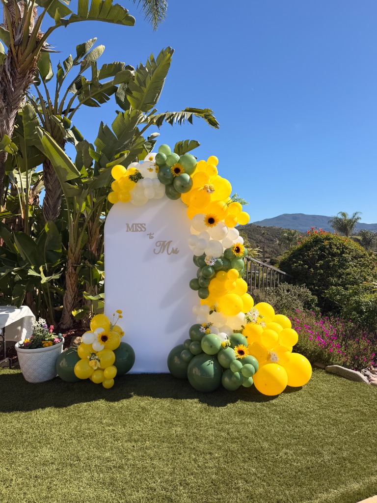 Miss to Mrs bridal shower backdrop with yellow and green balloons outdoors