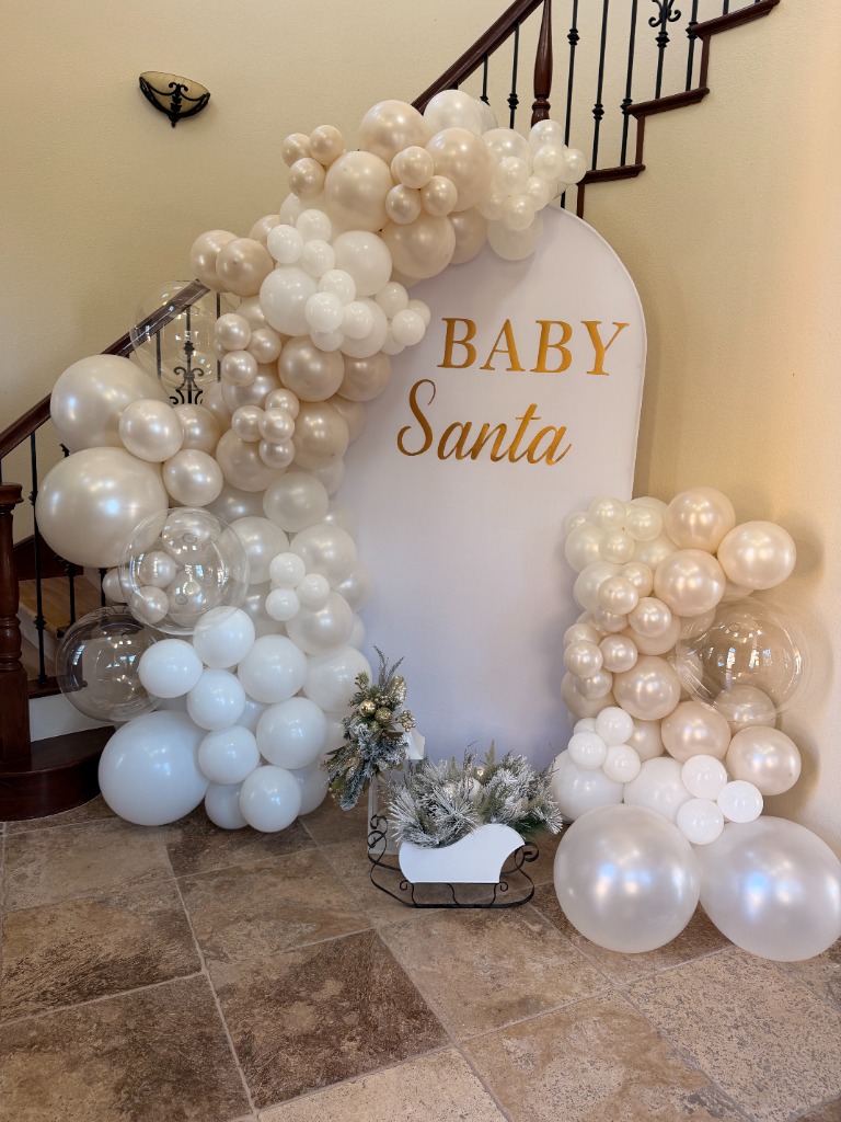 Winter wonderland Baby Santa party decor with white balloons and frosted mini trees