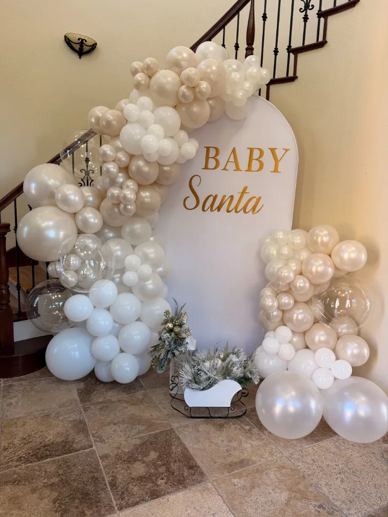 Winter wonderland Baby Santa party decor with white balloons and frosted mini trees